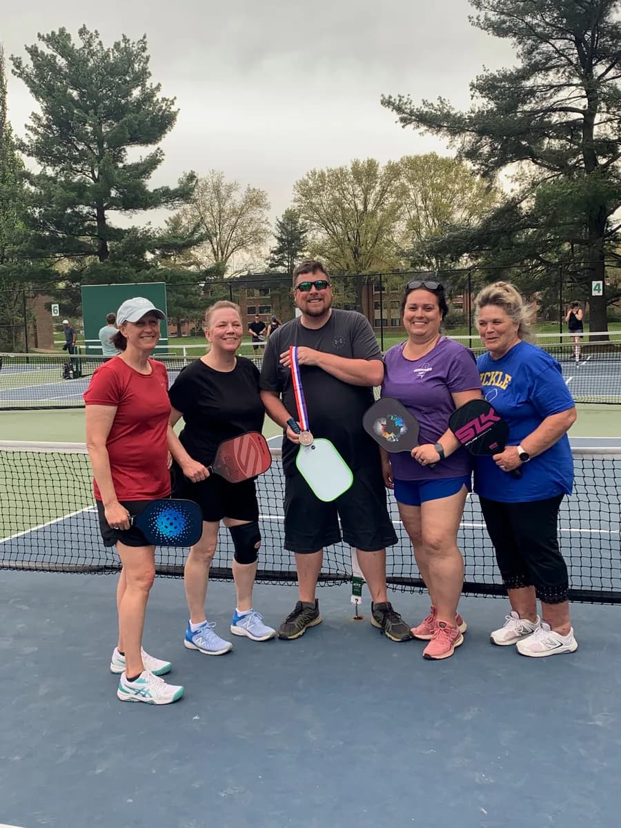 Pickleball players gathered together with their paddles on an outdoor court