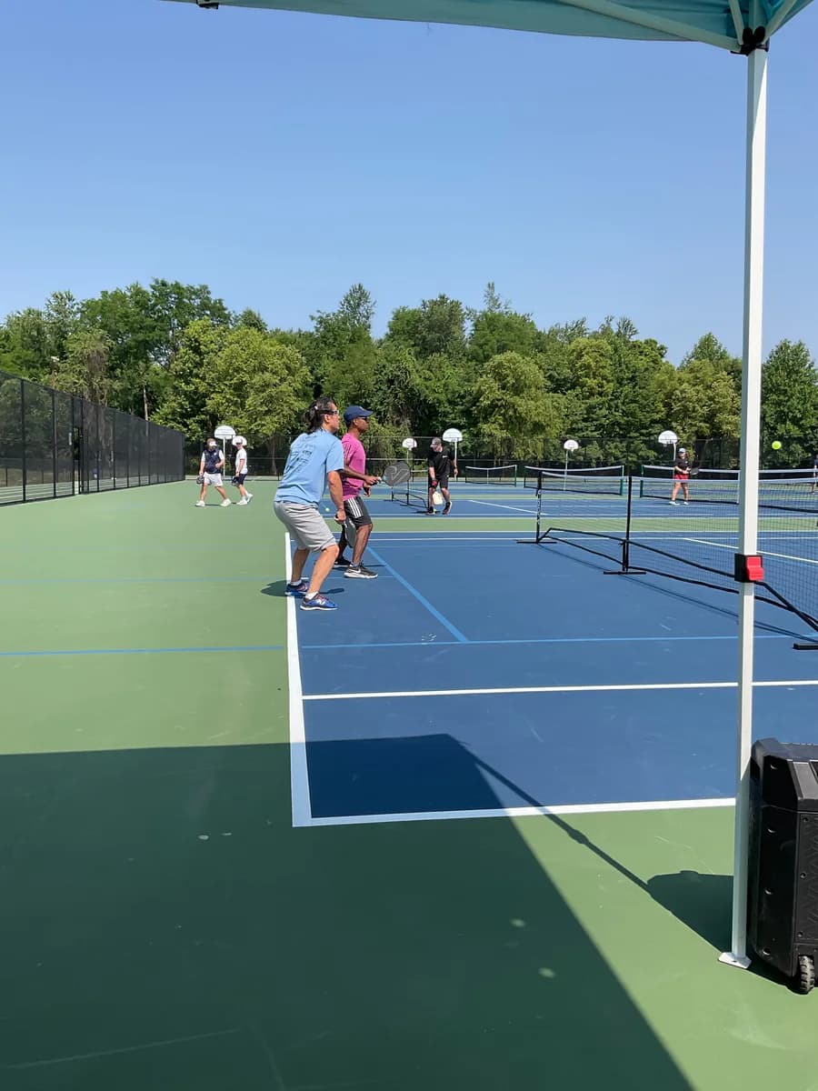 Pickleball players preparing for or playing a doubles rally on outdoor courts