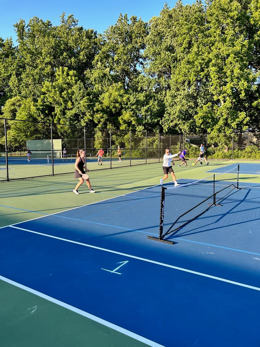 Pickleball players preparing for or playing a doubles rally on outdoor courts