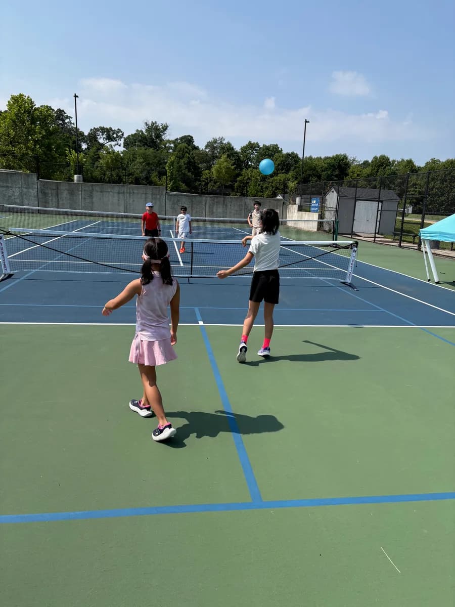 Young pickleball players practicing a rally across an outdoor net