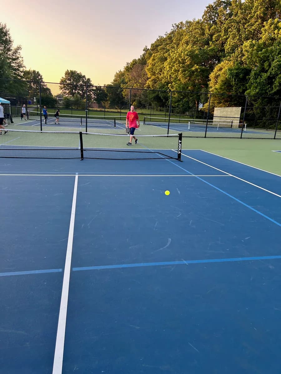 Pickleball players preparing for or playing a doubles rally on outdoor courts