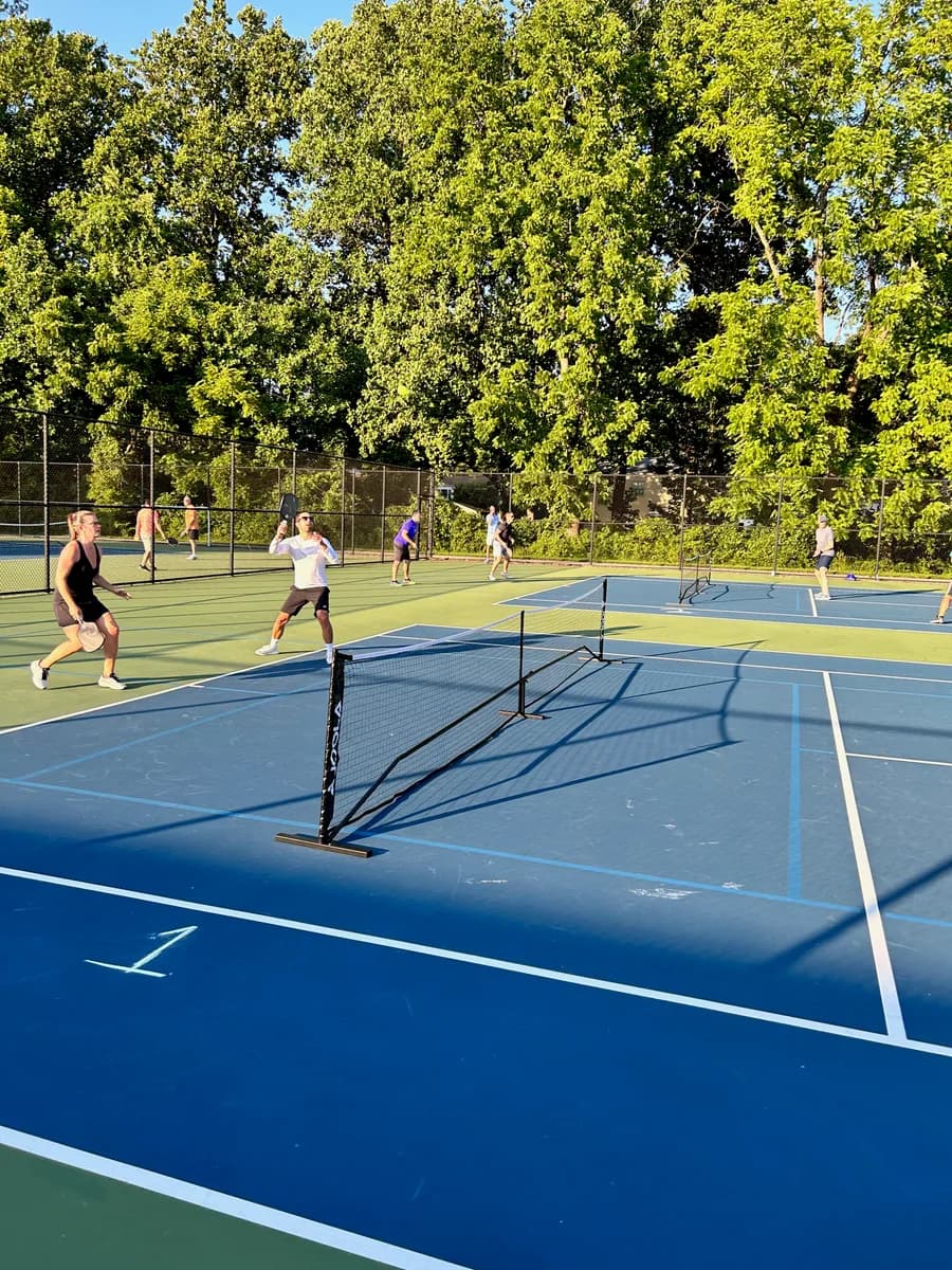 Pickleball players preparing for or playing a doubles rally on outdoor courts