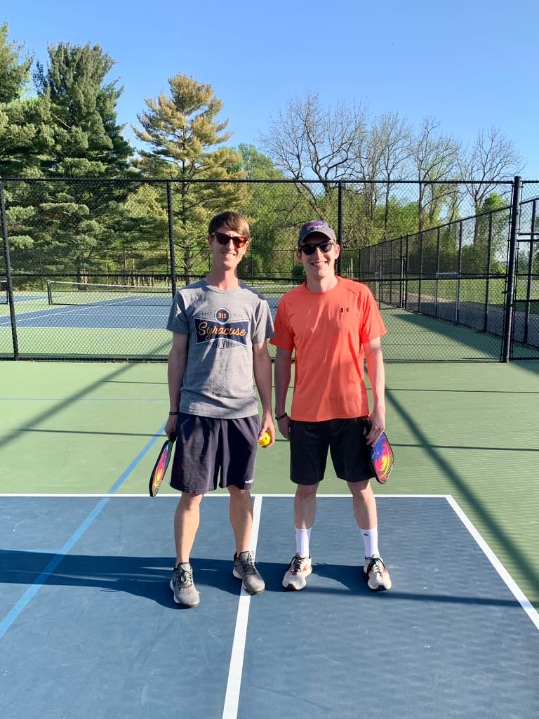 Two pickleball players smiling and holding their paddles outdoors