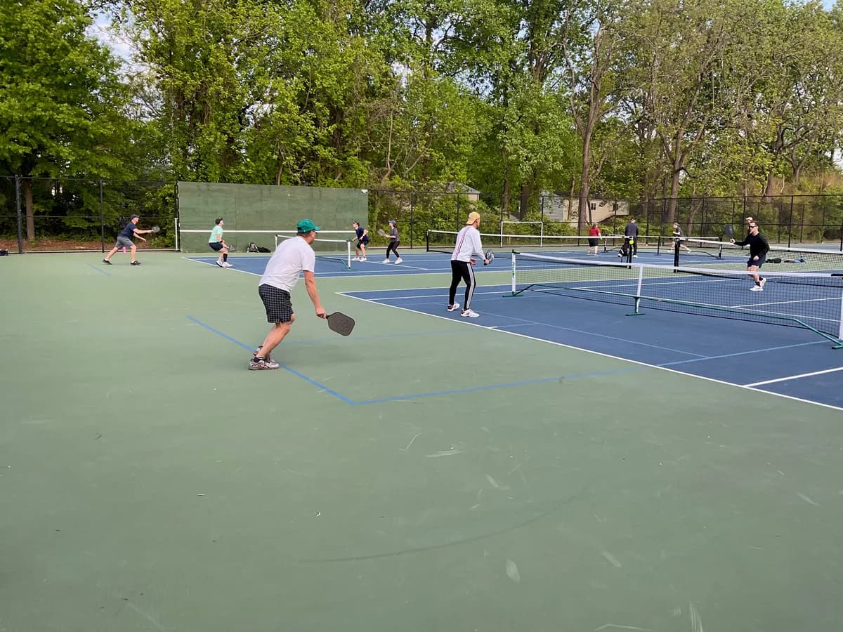 Pickleball players preparing for or playing a doubles rally on outdoor courts