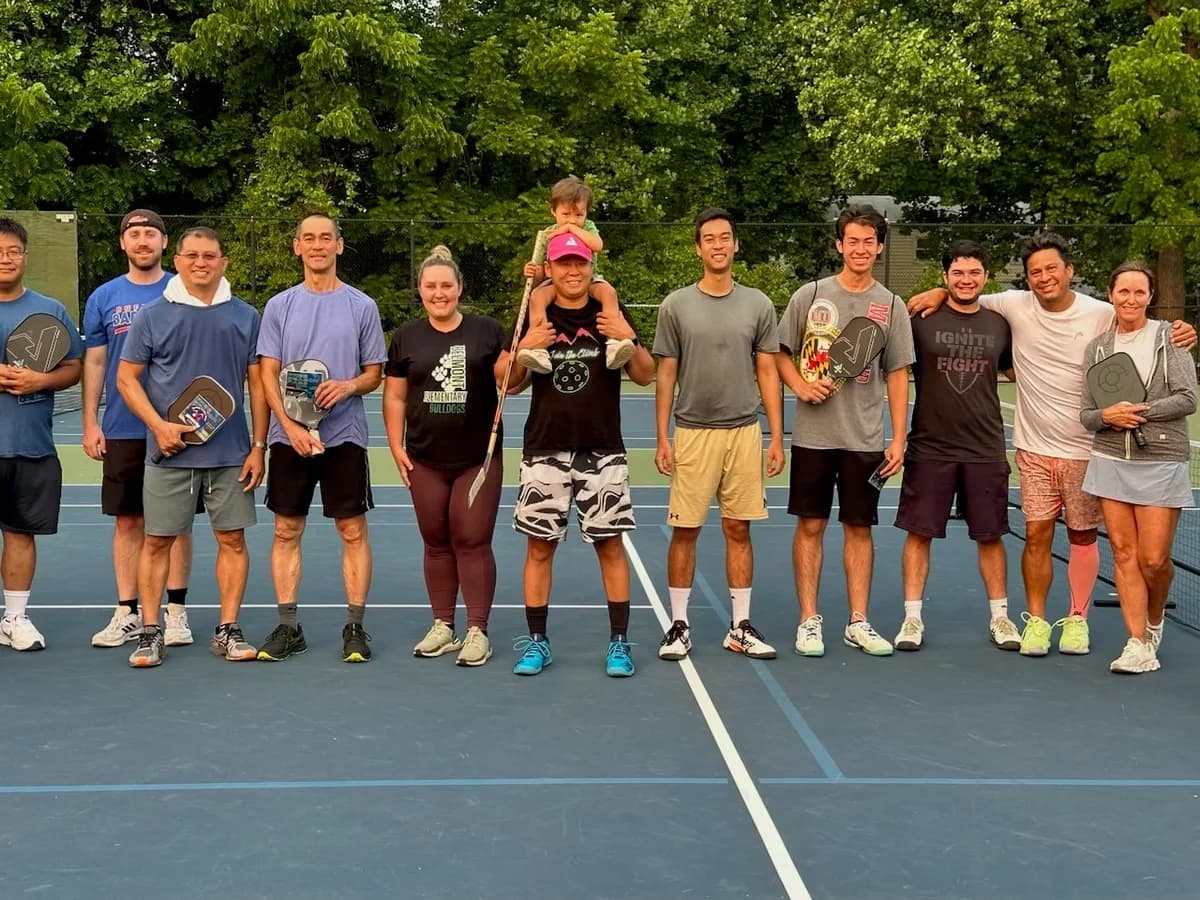 Pickleball players gathered together with their paddles on an outdoor court