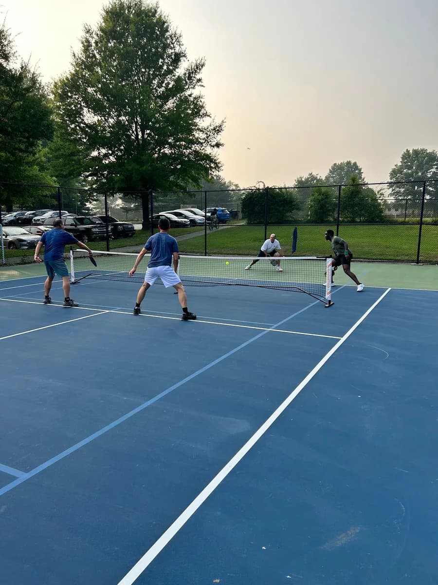 Pickleball players preparing for or playing a doubles rally on outdoor courts