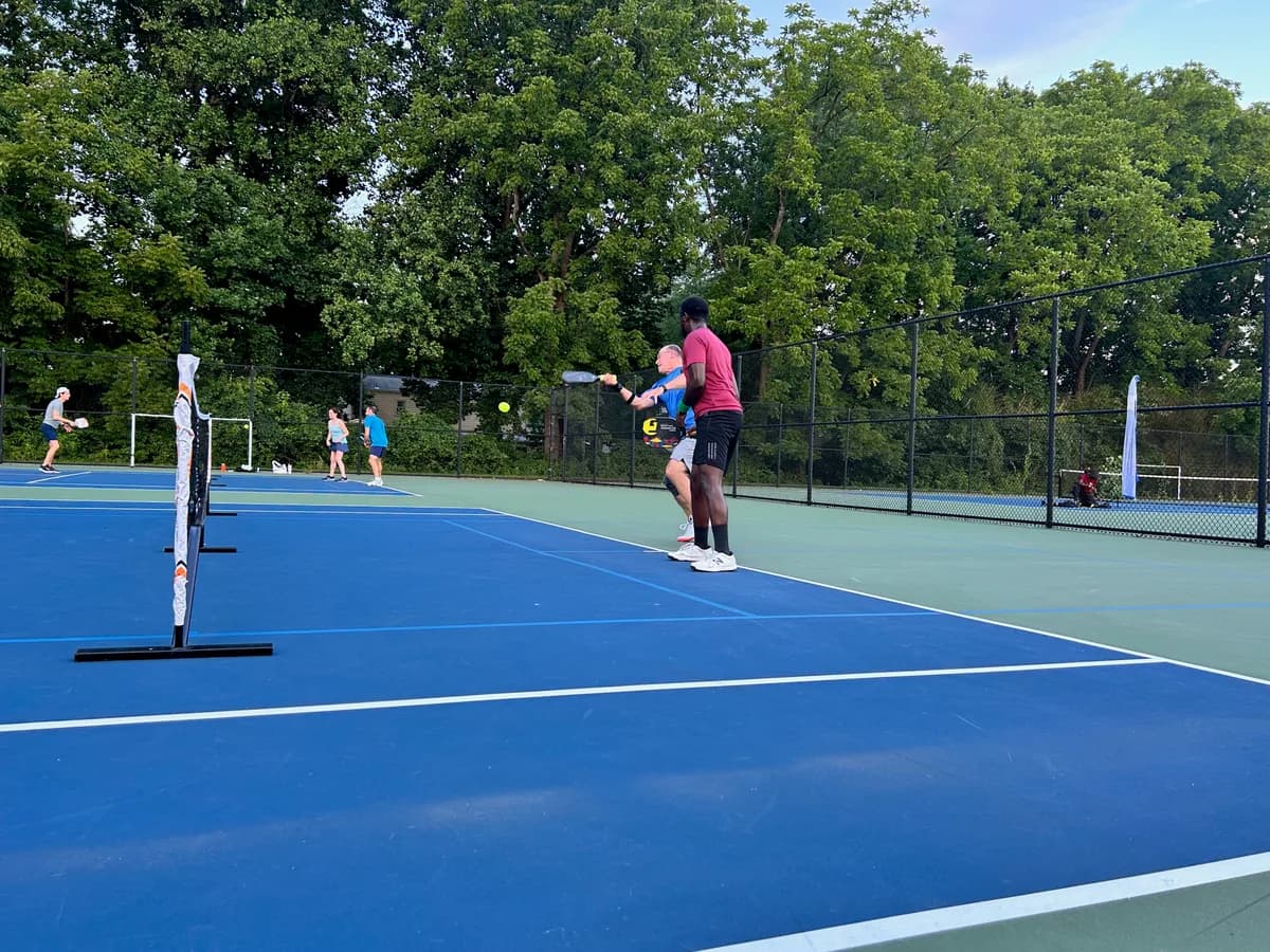 Pickleball players preparing for or playing a doubles rally on outdoor courts
