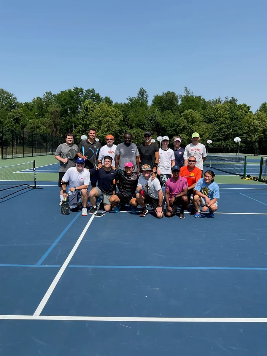 Pickleball players gathered together with their paddles on an outdoor court