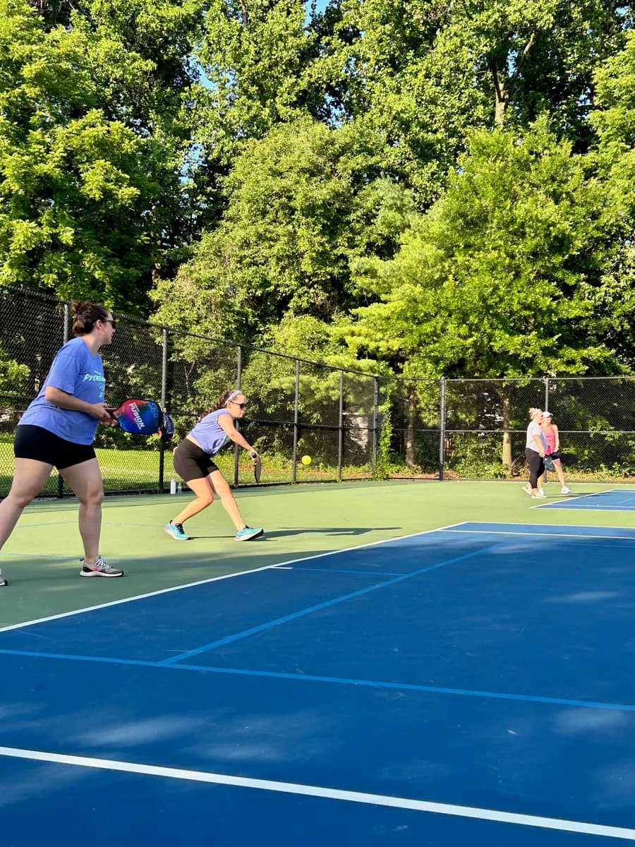 Pickleball players preparing for or playing a doubles rally on outdoor courts