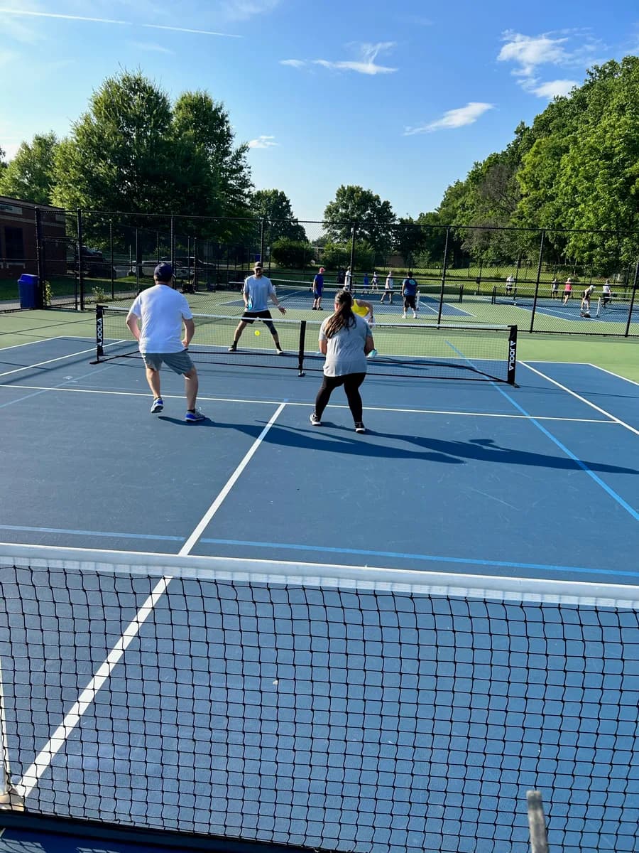Pickleball players preparing for or playing a doubles rally on outdoor courts