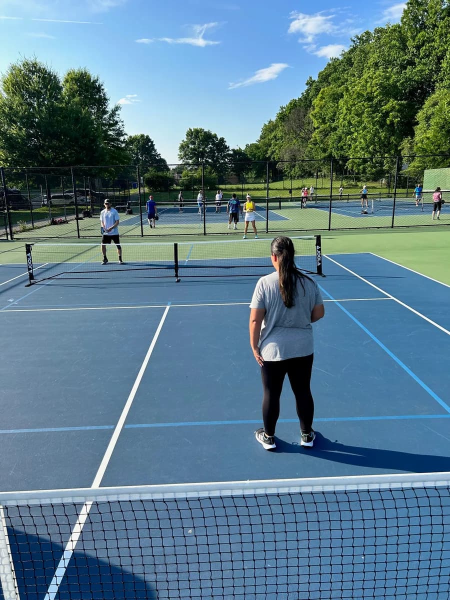 Pickleball players preparing for or playing a doubles rally on outdoor courts