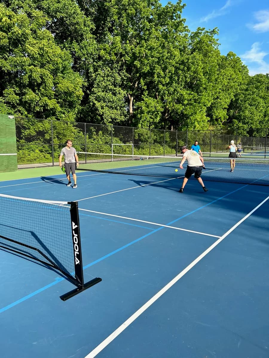 Pickleball players preparing for or playing a doubles rally on outdoor courts
