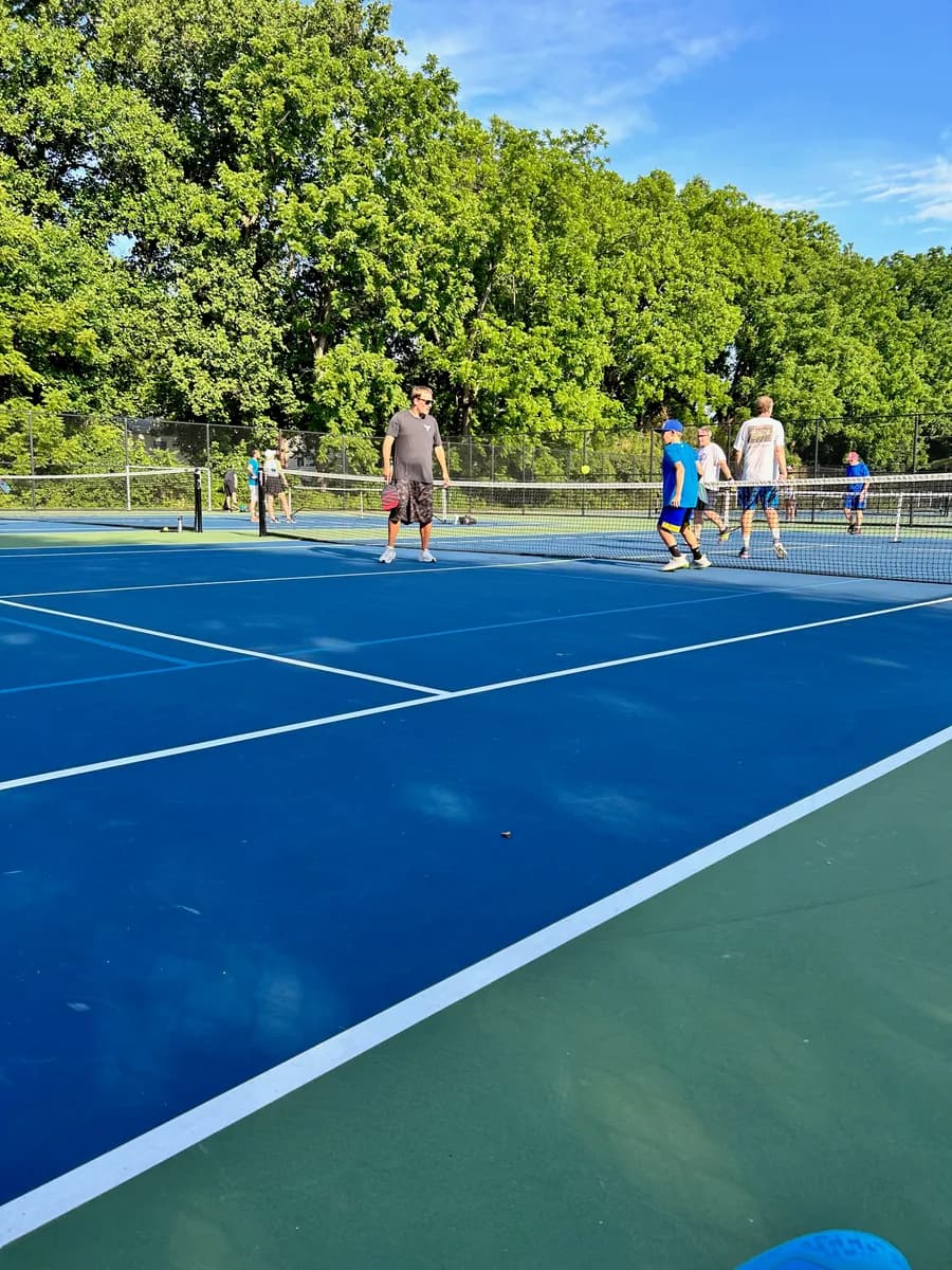 Pickleball players preparing for or playing a doubles rally on outdoor courts