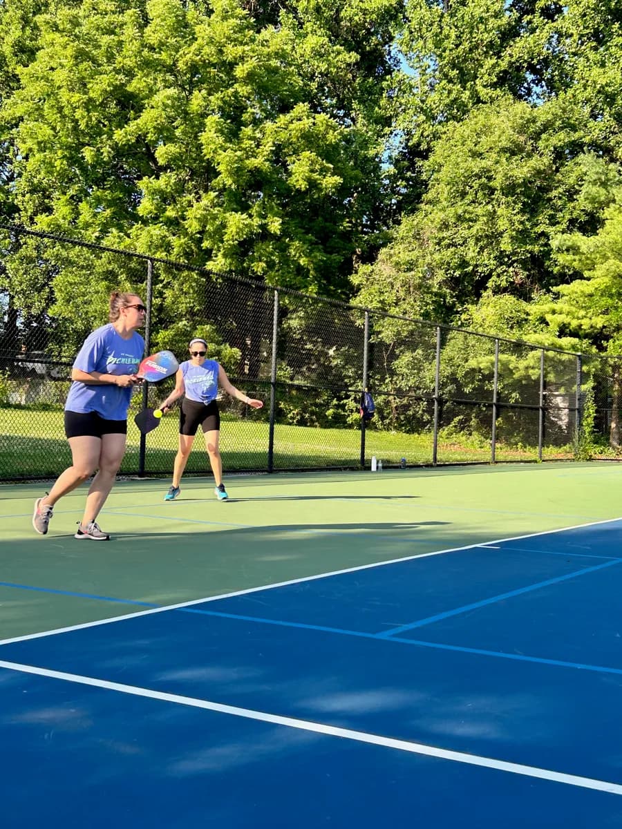 Pickleball players preparing for or playing a doubles rally on outdoor courts