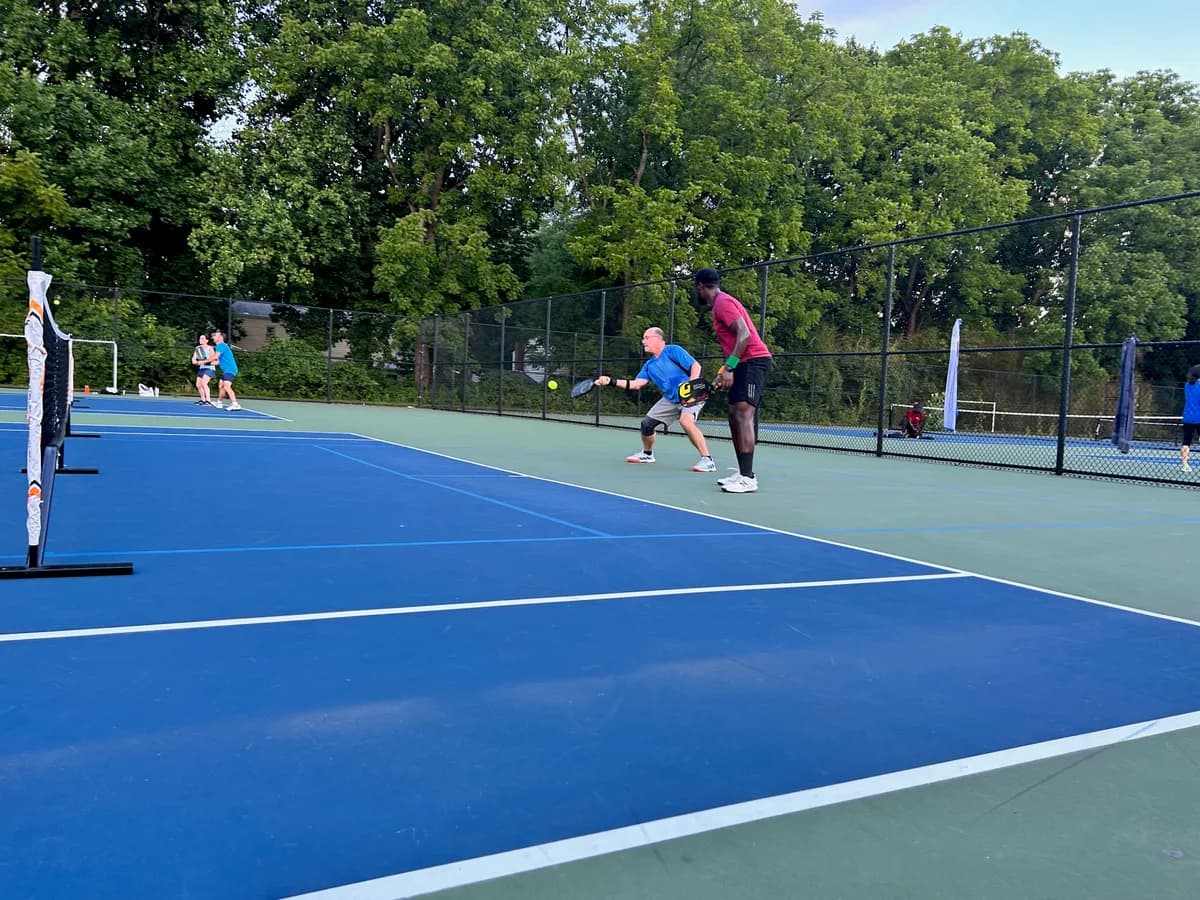 Pickleball players preparing for or playing a doubles rally on outdoor courts