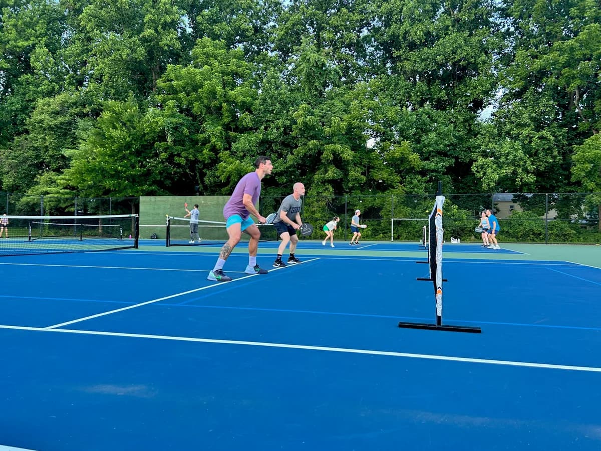 Pickleball players preparing for or playing a doubles rally on outdoor courts